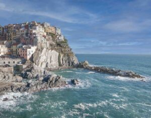 A rocky cliff with water and sky in the background